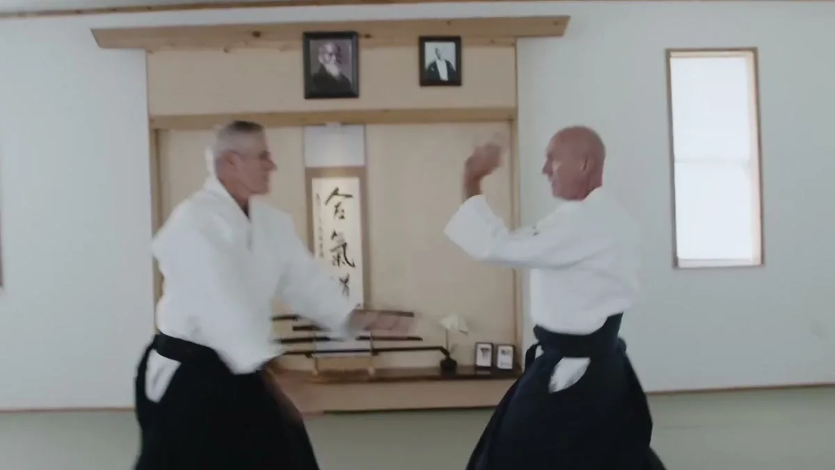 Two Kimusubi Aikido practitioners training with focused posture in the dojo